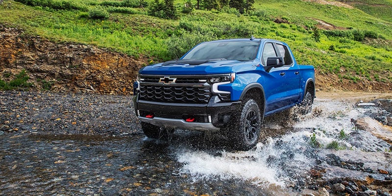 Chevrolet Silverado 1500 powering through water, highlighting its tough, all-terrain design.
